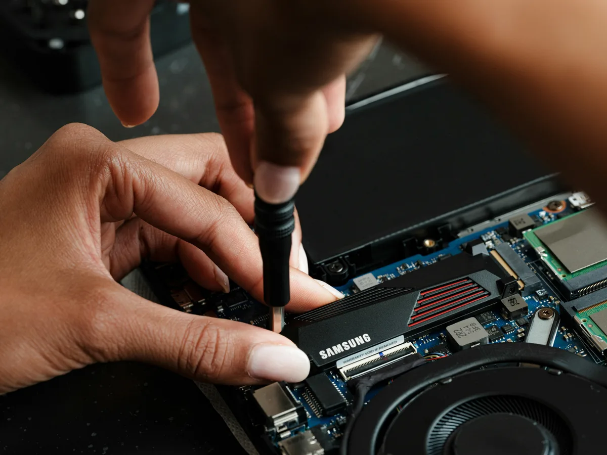 Instalação de SSD em notebook aberto, com a placa e o cooler à vista